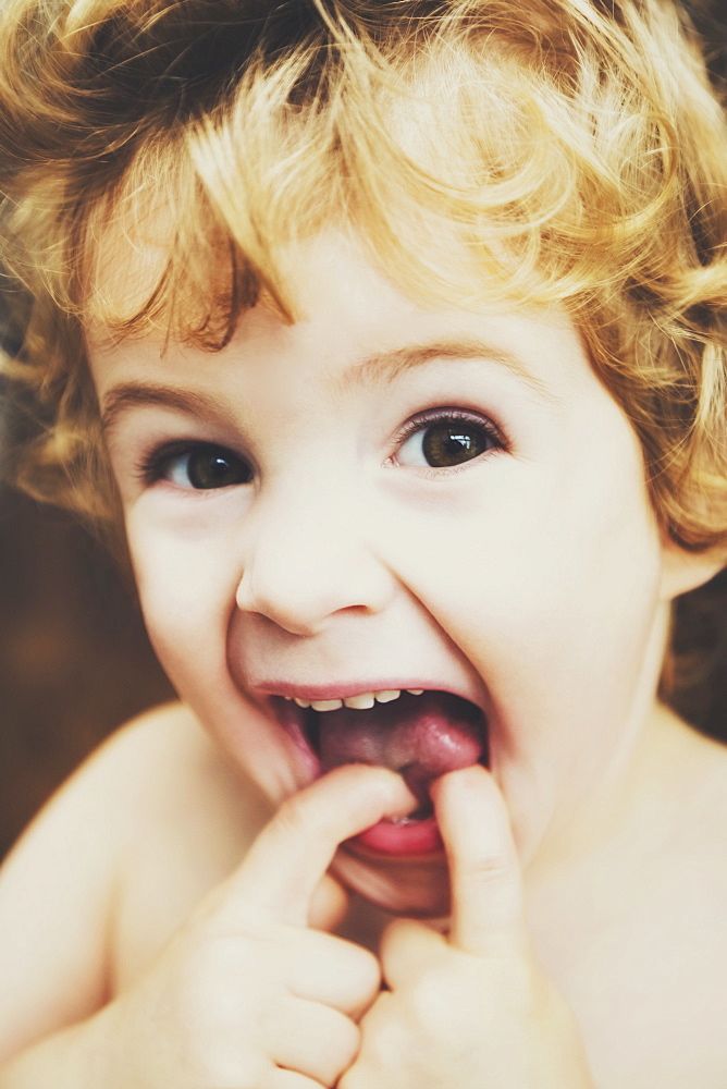 Toddler Making Funny Faces At The Camera And Putting His Fingers in His Mouth, Langley, British Columbia, Canada