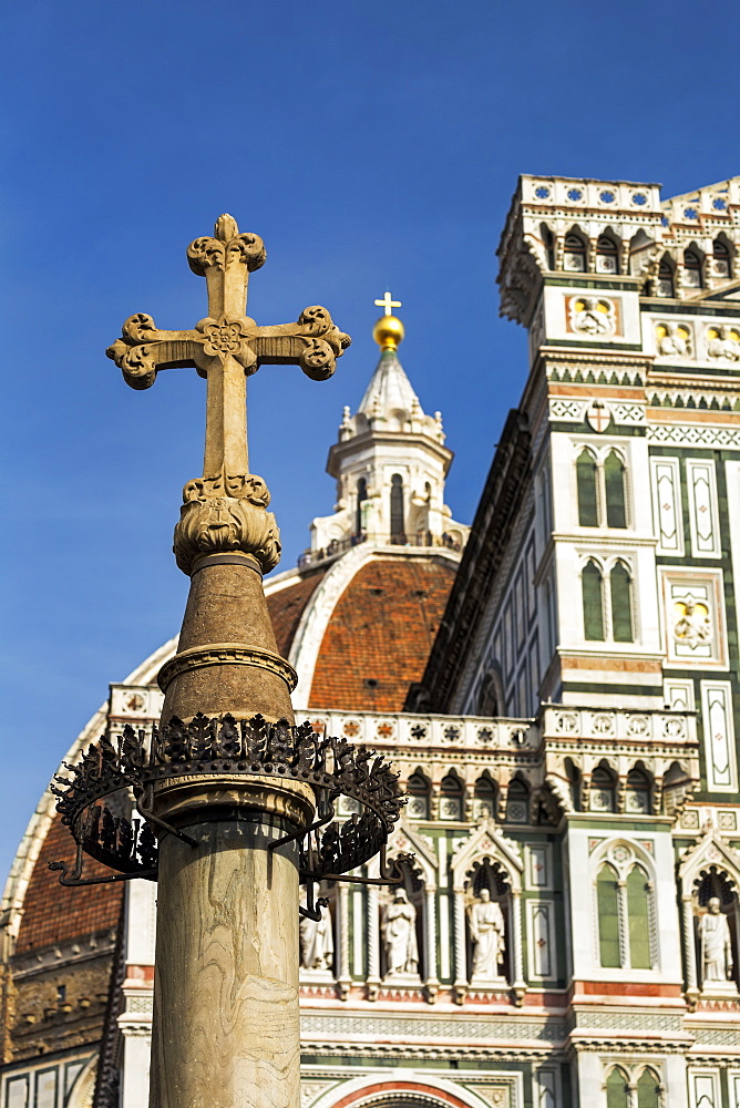 Stone cross with the decorative dome and facade of Florence Cathedral with blue sky, Florence, Tuscany, Italy