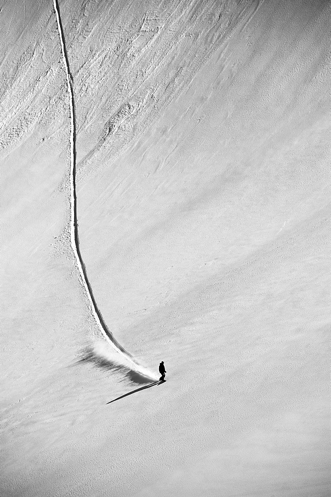 A professional, freeriding snowboarder on a wide open snowy slope making new tracks, British Columbia, Canada