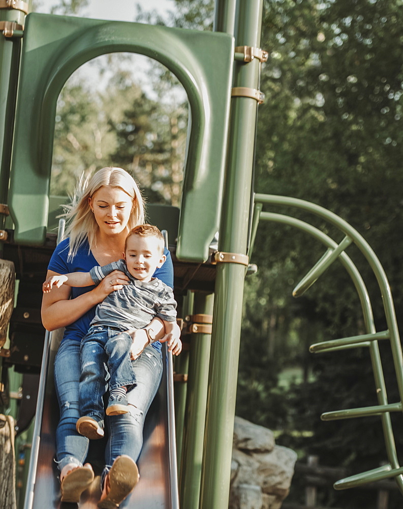 Mother on a slide with young son, Edmonton, Alberta, Canada