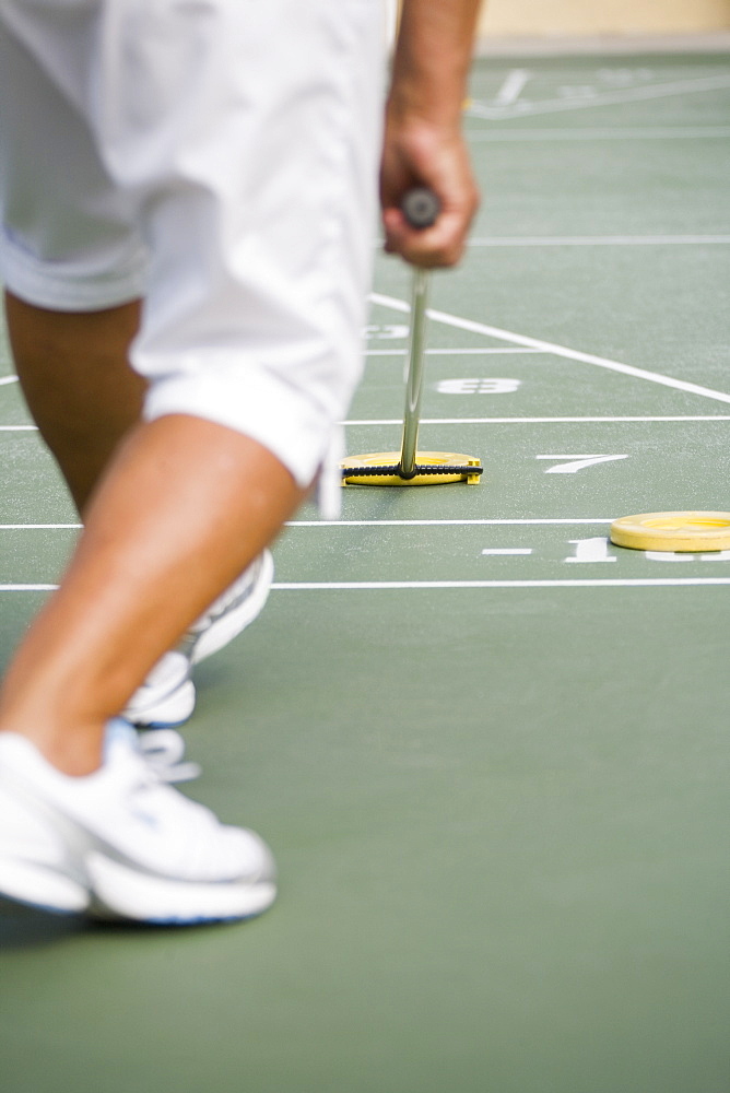 Low section view of a senior man playing shuffleboard