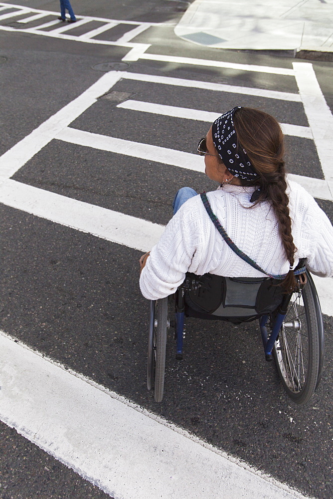 Woman with spinal cord injury in wheelchair crossing street