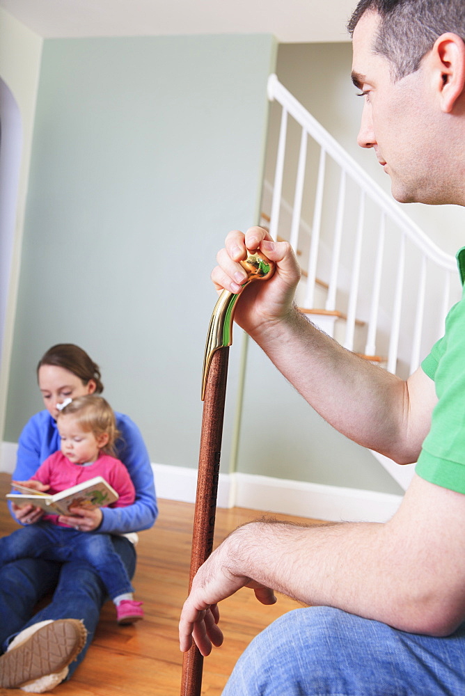 Man after anterior cruciate ligament (ACL) surgery with wife and daughter at home