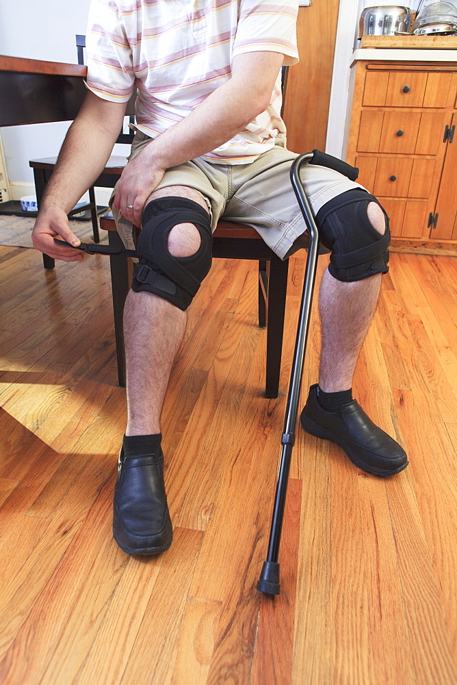 Man adjusting braces on his knees after anterior cruciate ligament (ACL) surgery