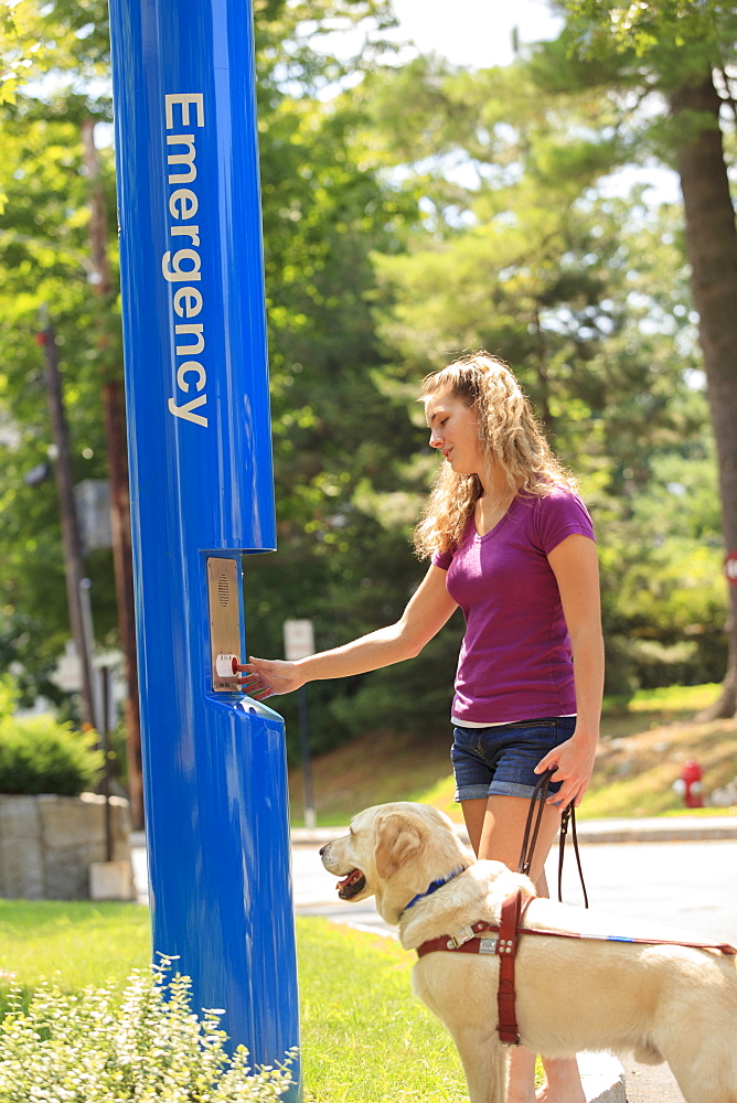 Student with visual impairment and her service dog using Emergency station at school