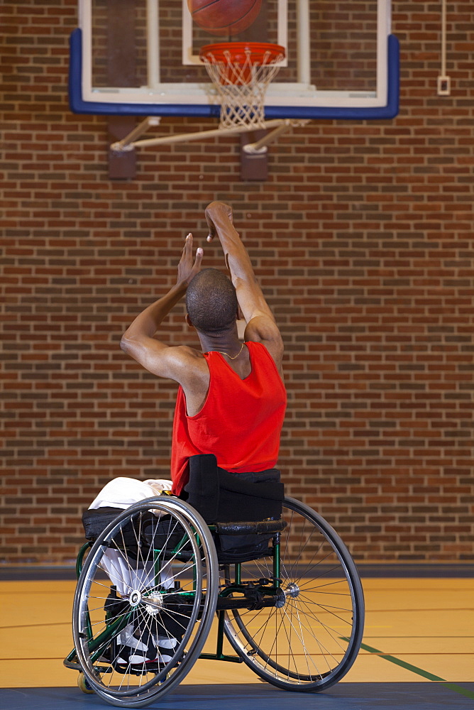 Man who had Spinal Meningitis in wheelchair taking a net shot in basketball