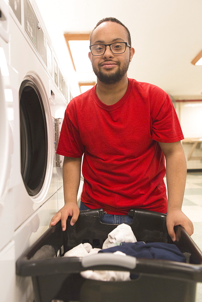 African American man with Down Syndrome doing laundry in utility room