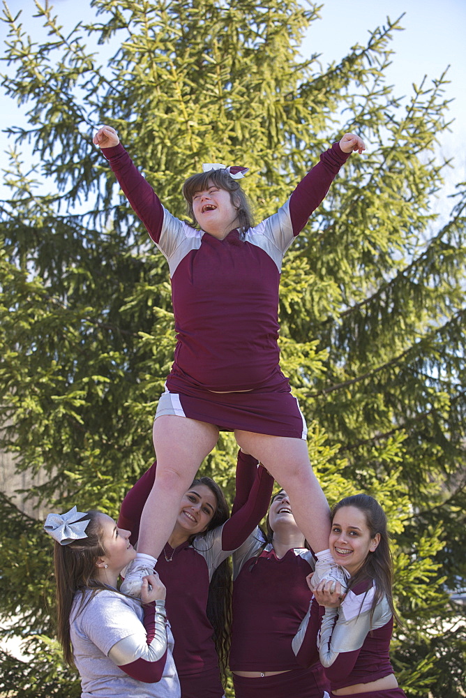 Cheerleaders lifting a cheerleader with Down Syndrome in the air