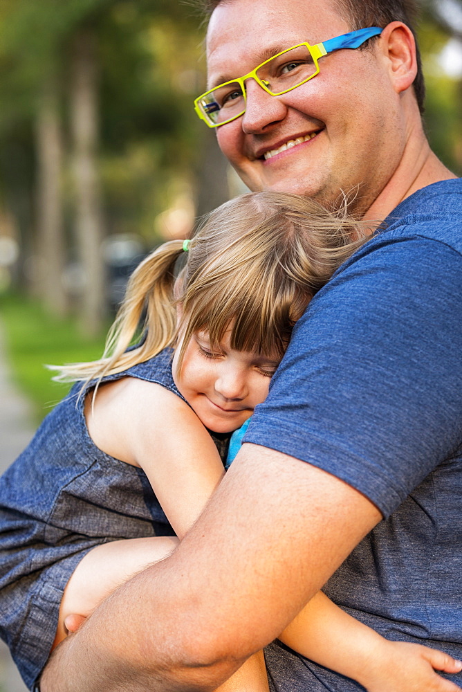 Portrait of a father cuddling with his young daughter; Edmonton, Alberta, Canada