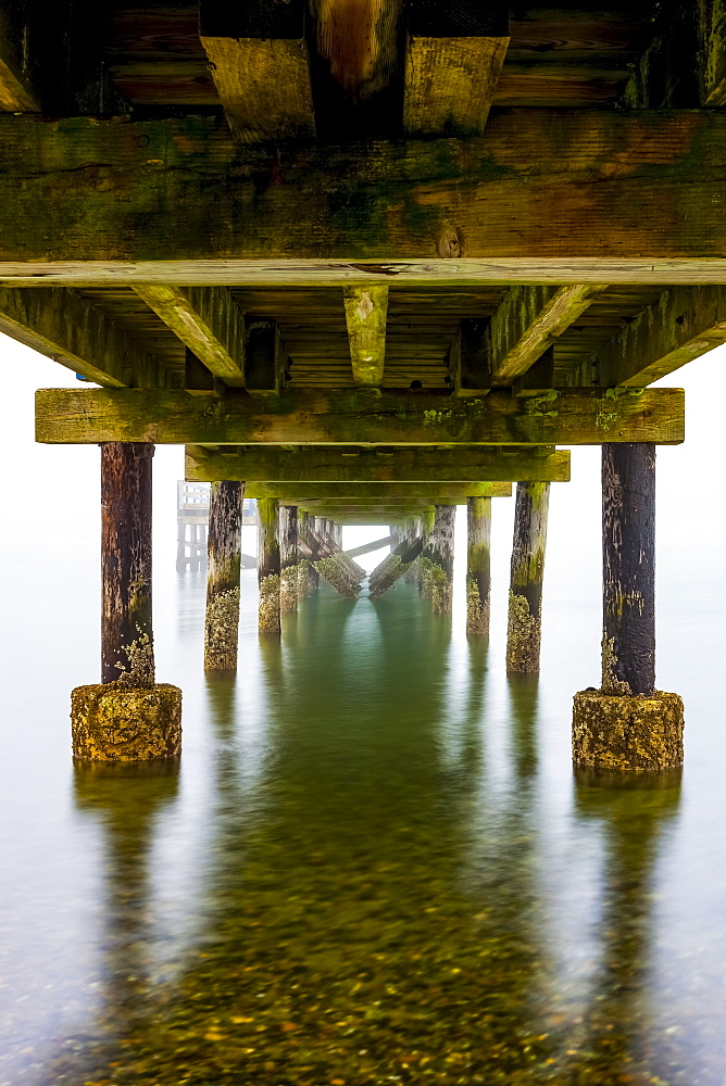 Underneath the pier on Crescent Beach on a foggy day; Surrey, British Columbia, Canada