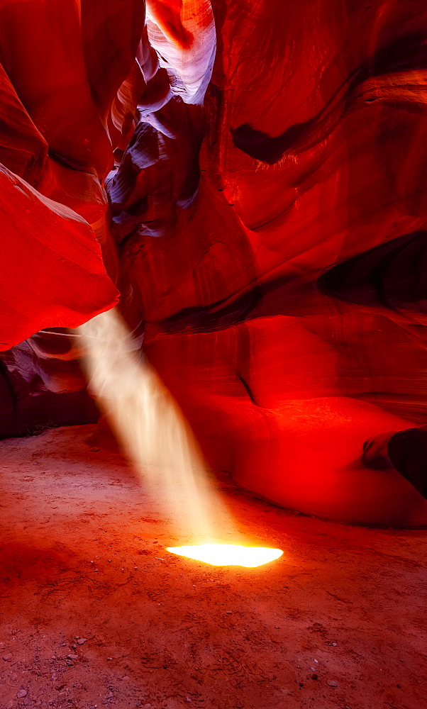 Upper Antelope Canyon with a beam of sunlight shining through a hole resembling a spotlight to the ground; Arizona, United States of America