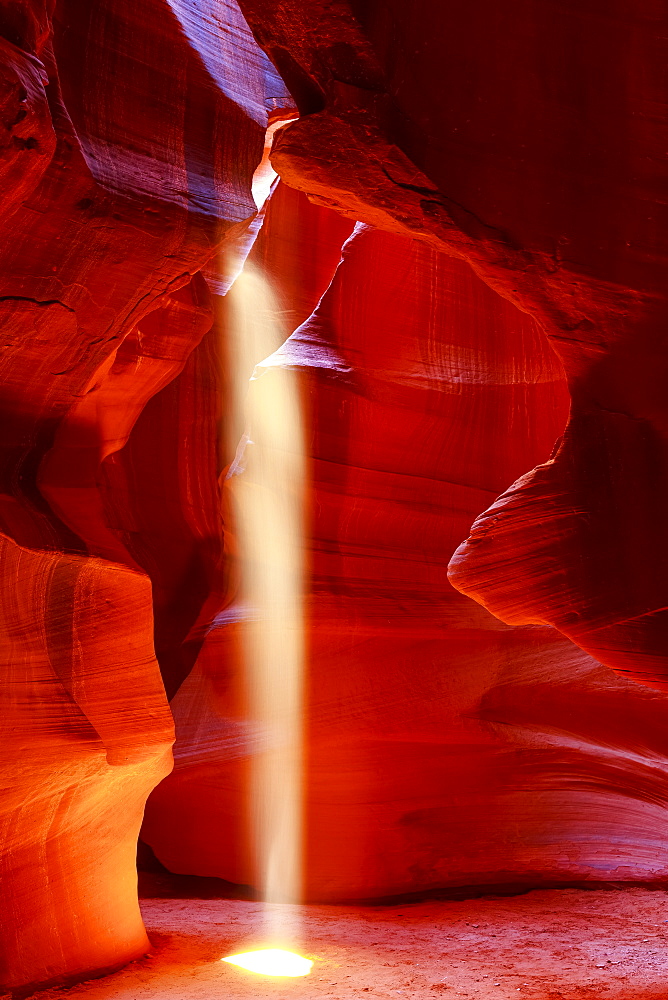 Upper Antelope Canyon with a beam of sunlight shining through a hole resembling a spotlight to the ground; Arizona, United States of America