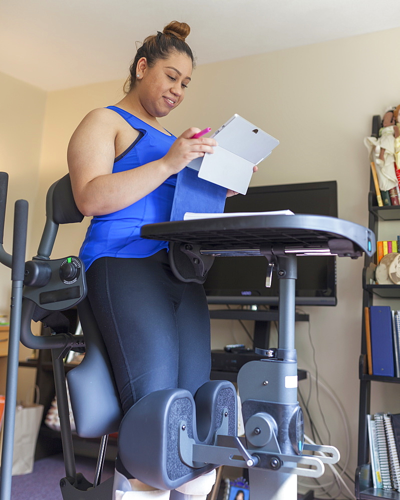 Latina woman with spinal cord injury working at home at a stand up desk