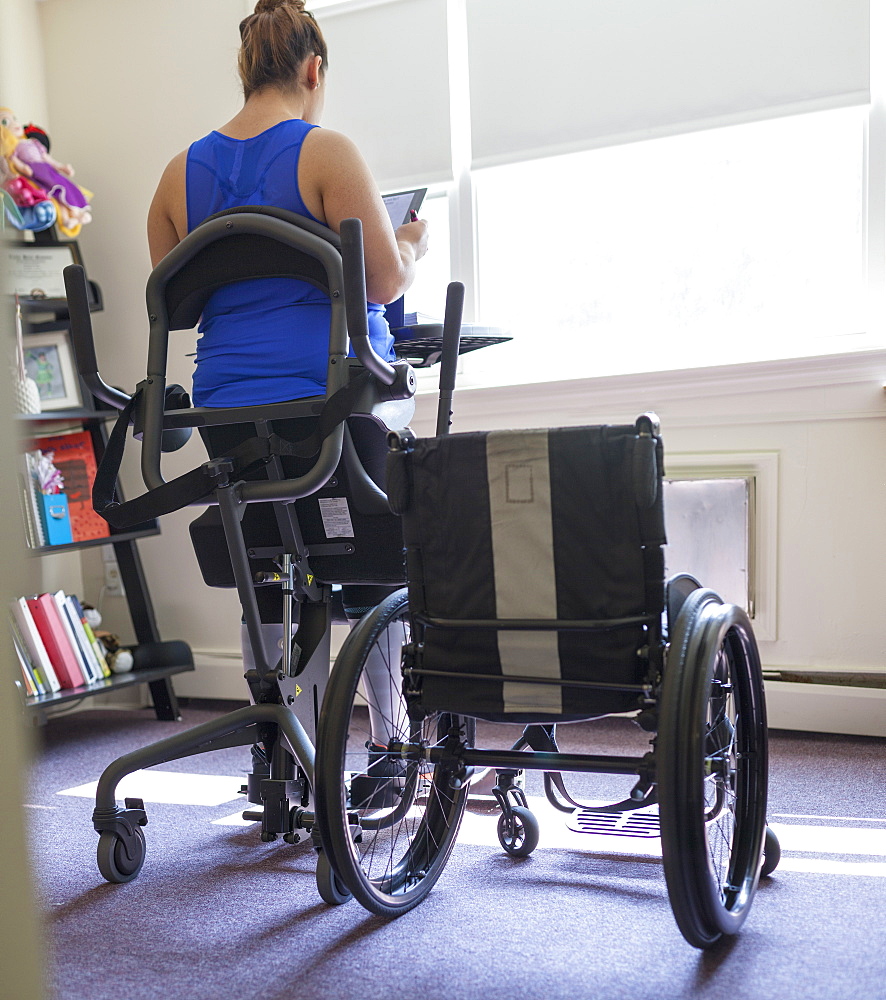 Woman with spinal cord injury working at home at her stand up desk