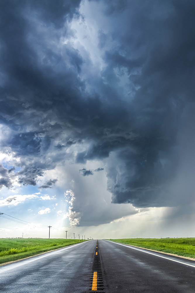 A developing severe thunderstorm with large hail crosses the highway in Colorado, near Burlington; Colorado, United States of America