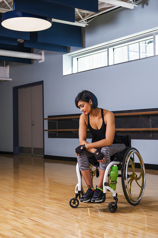 A paraplegic woman looking discouraged while taking a break from working out in a recreational facility: Edmonton, Alberta, Canada