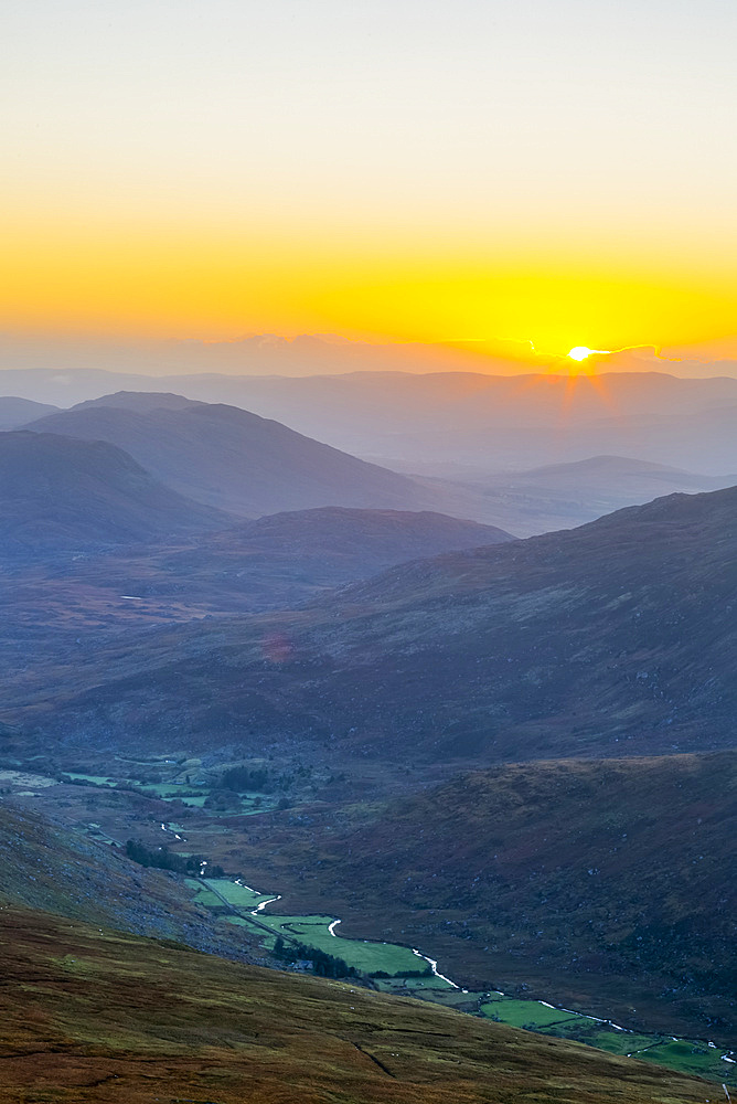 Sun rising over the Owenreagh River in the Gearsallagh Valley in MacGillycuddy's Reeks; County Kerry, Ireland