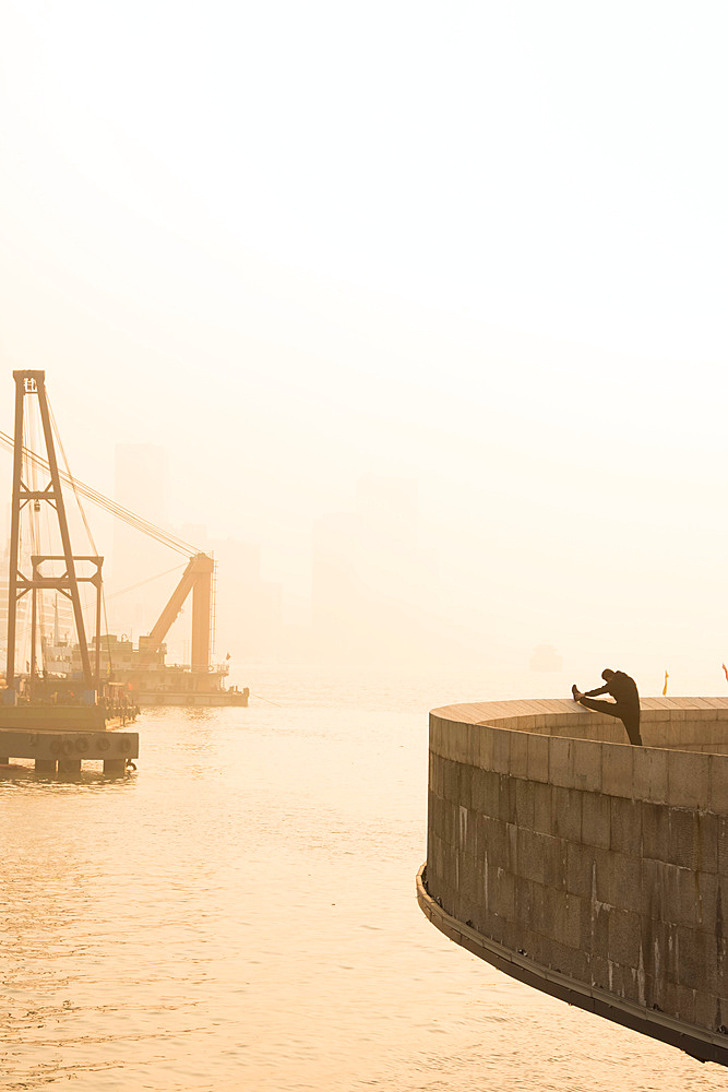 Man doing morning stretches by the Bund in Shanghai; Shanghai, Shanghai, China