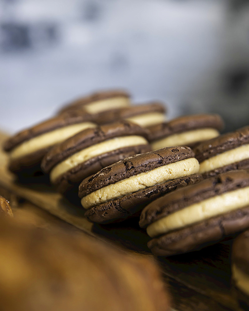 Chocolate and cream cookies lined up on wooden board; Melbourne, Victoria, Australia