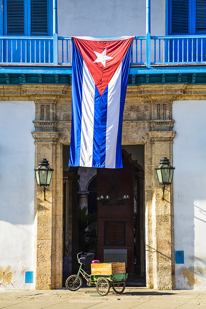 The national flag of Cuba hangs over the entrance to the Palace of the Artisans (Palacio de la Artesania), Old Town; Havana, Cuba