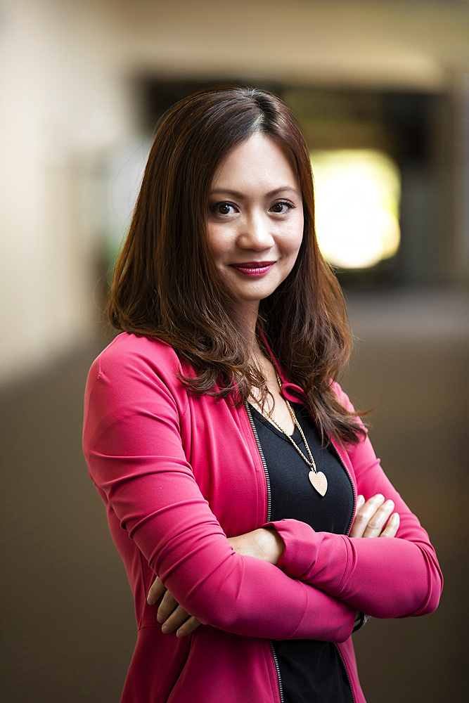 A close-up portrait of an Asian business woman in a hallway at her place of work: Edmonton, Alberta, Canada