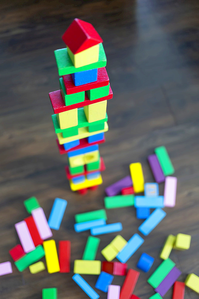 Colourful blocks stacked into a tower and dispersed on the floor at playtime; Surrey, British Columbia, Canada