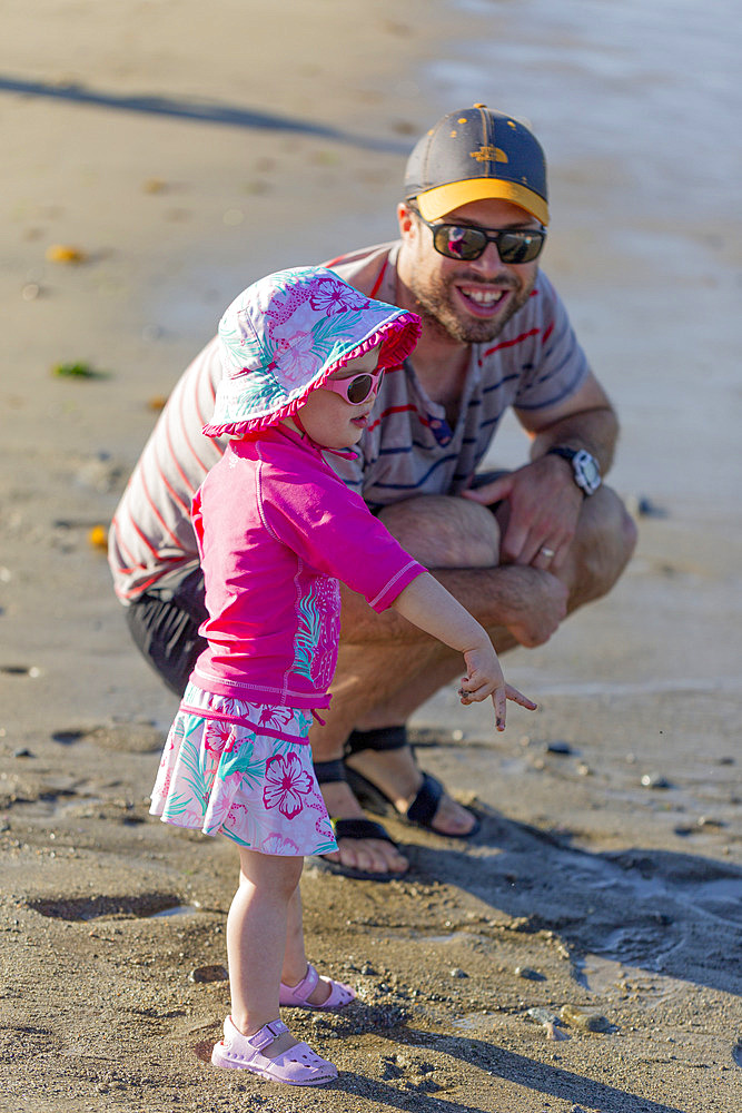 A father spends quality time with his toddler daughter at the water's edge at Ambleside Beach; West Vancouver, British Columbia, Canada