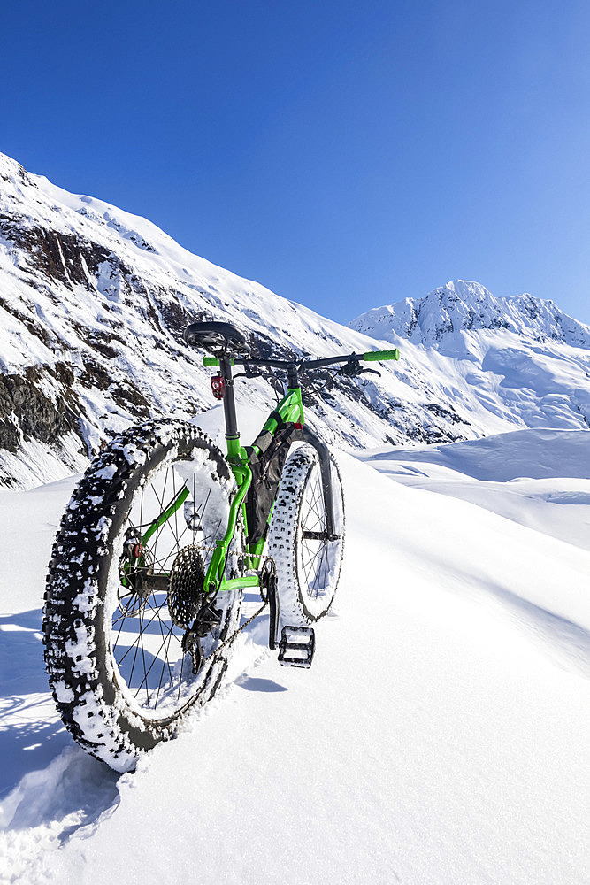 Green fat tire bike on a sunny winter day at Skookum Glacier, Chugach National Forest; Alaska, United States of America