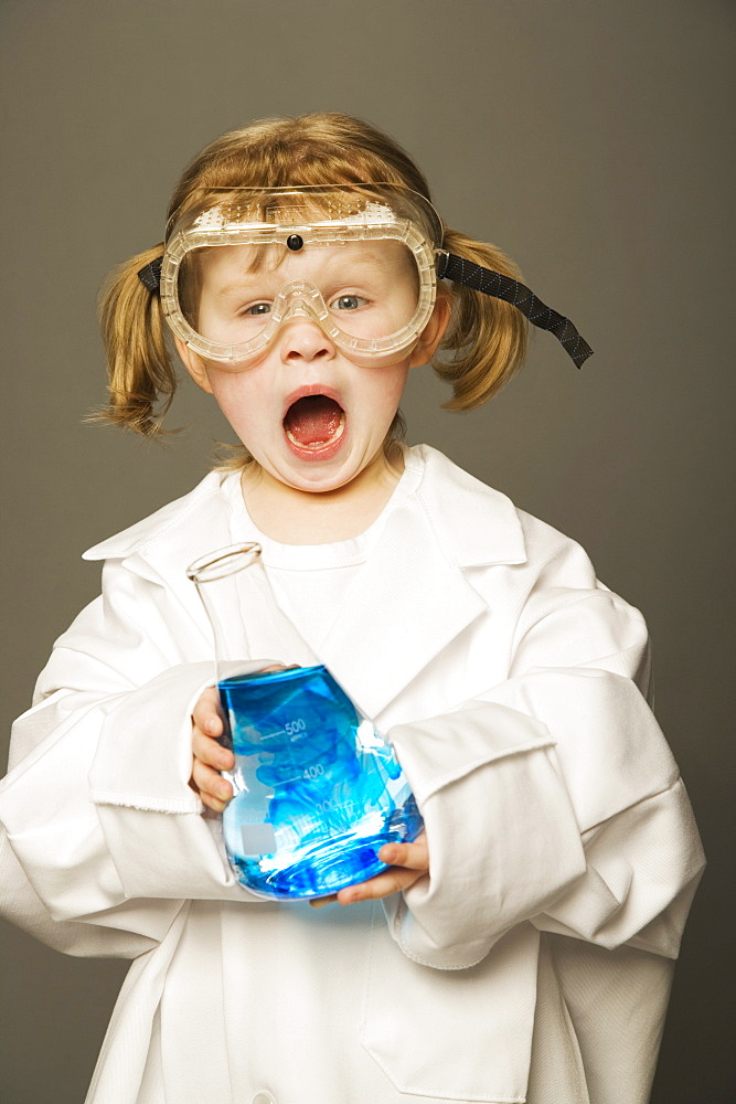 Little Girl With Safety Goggles And Lab Coat Holding A Science Beaker