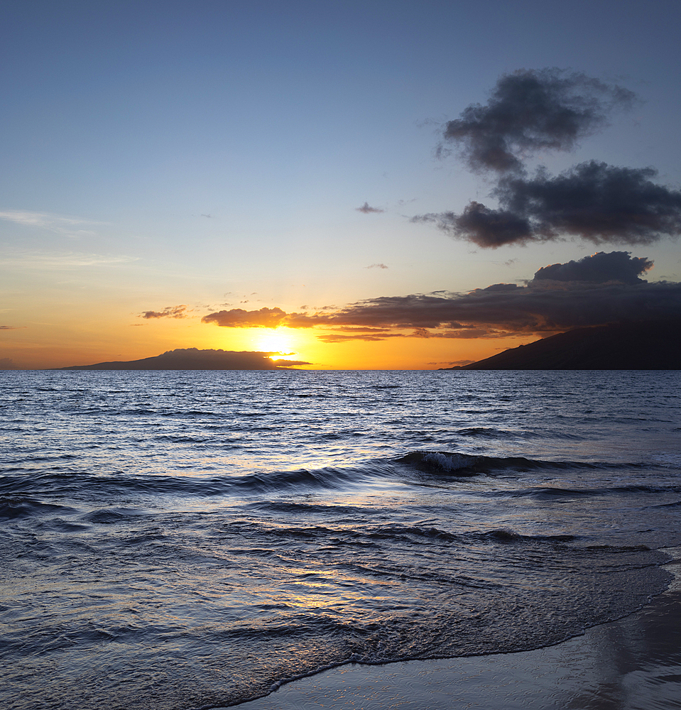 Ocean waves along the shoreline of Kamaole 2 Beach at twilight with a golden sun, Kihei, Maui, Hawaii, United States of America