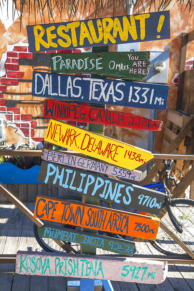 Close-up of colorful mileage signs for multiple locations at a restaurant on Grand Cayman in the Cayman Islands, Grand Cayman, Cayman Islands, Caribbean