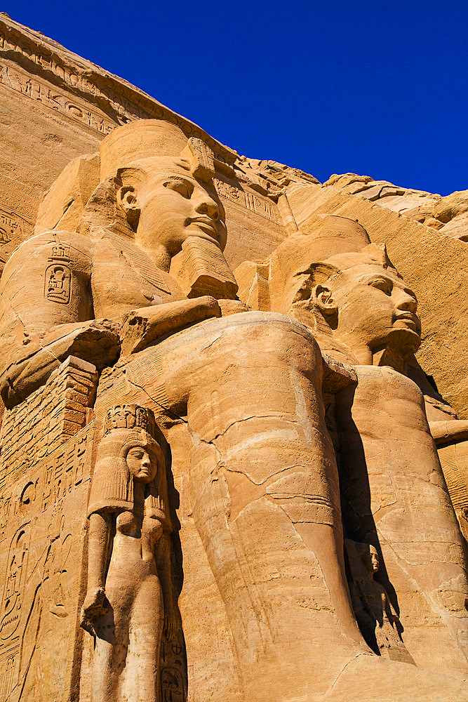 Close-up of two of the Ramses II statues carved out of the mountainside at the front of the Great Sun Temple of Abu Simbel, Abu Simbel, Nubia, Egypt