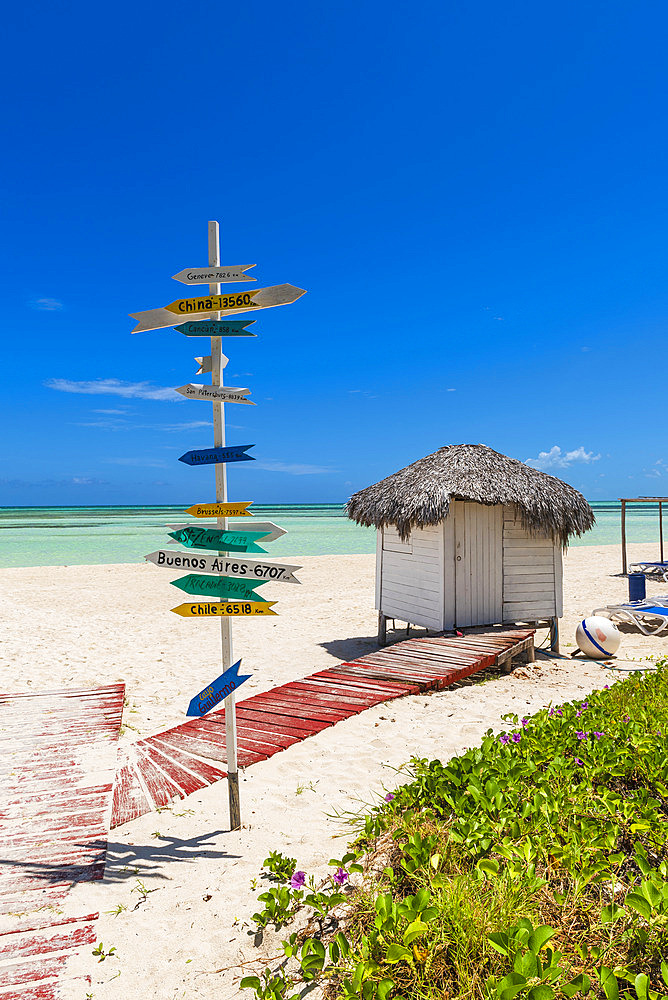 Signpost on a tropical white sand beach showing distance to countries around the world from Cuba in the Caribbean Sea, Cayo Guillermo, Cuba