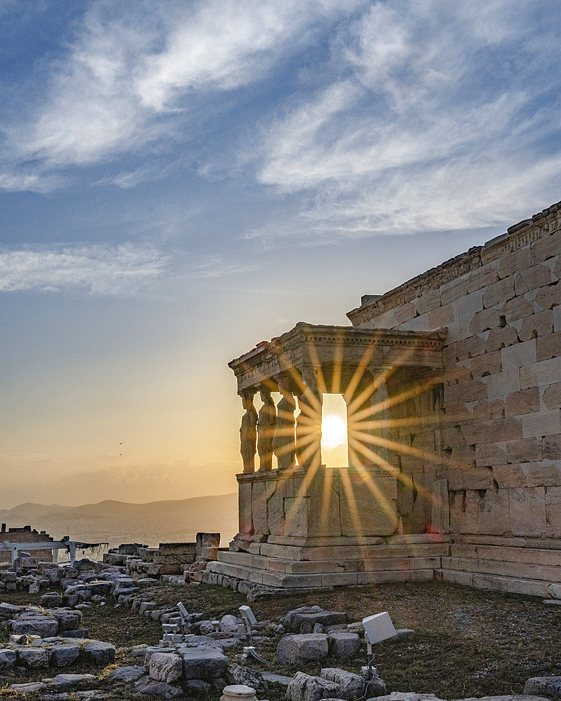 The Erechtheion (or Temple of Athena Polias) with sunburst on the Acropolis of Athens, the ancient citadel located on a rocky outcrop overlooking the City of Athens at twilight, Athens, Greece