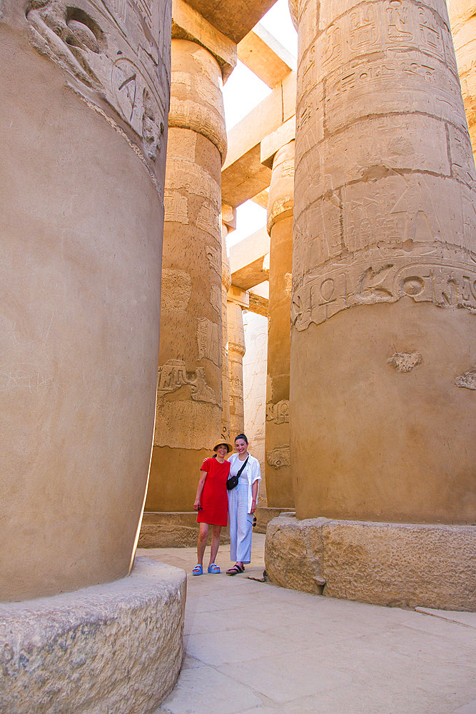 Two female tourists standing among the giant columns of Karnak Temple Complex, Luxor, Egypt