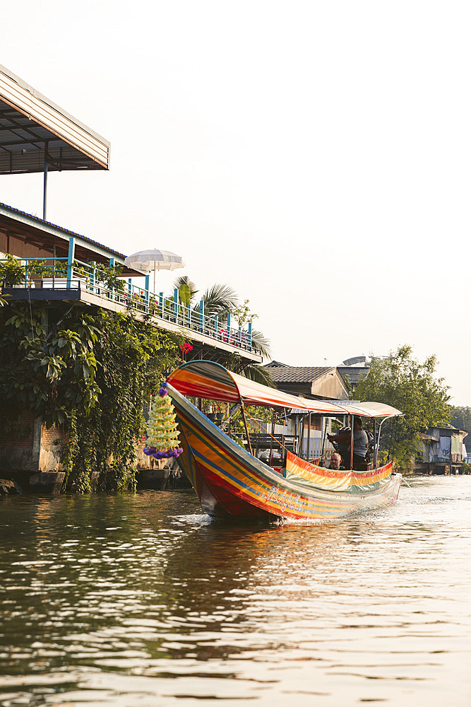 Traditional boat in colourful stripes travels along a river in Asia