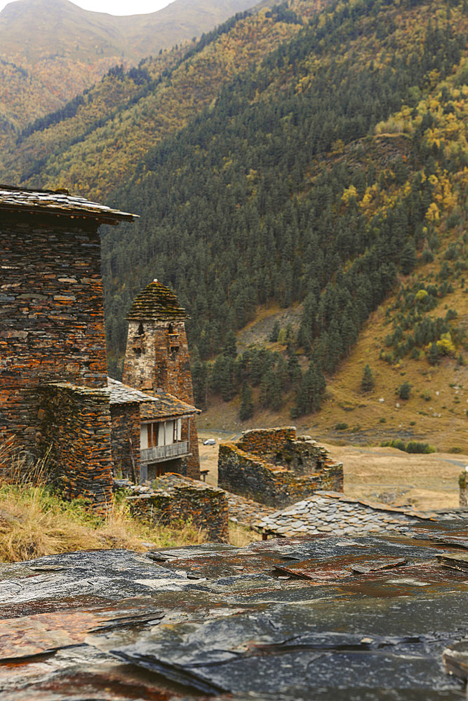 Historic stone house and tower with autumn coloured trees on the mountainside in the village of Dartlo in Tusheti National Park, Dartlo, Kakheti, Georgia