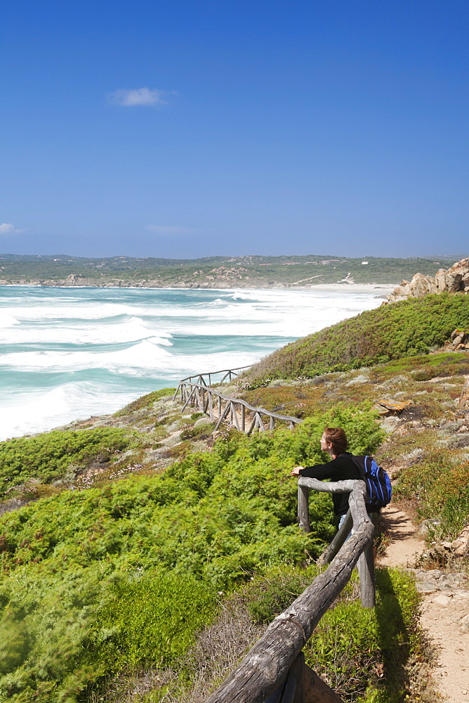 Woman at a path along the west coast at the beach of Rena Maiore, Sardinia, Italy