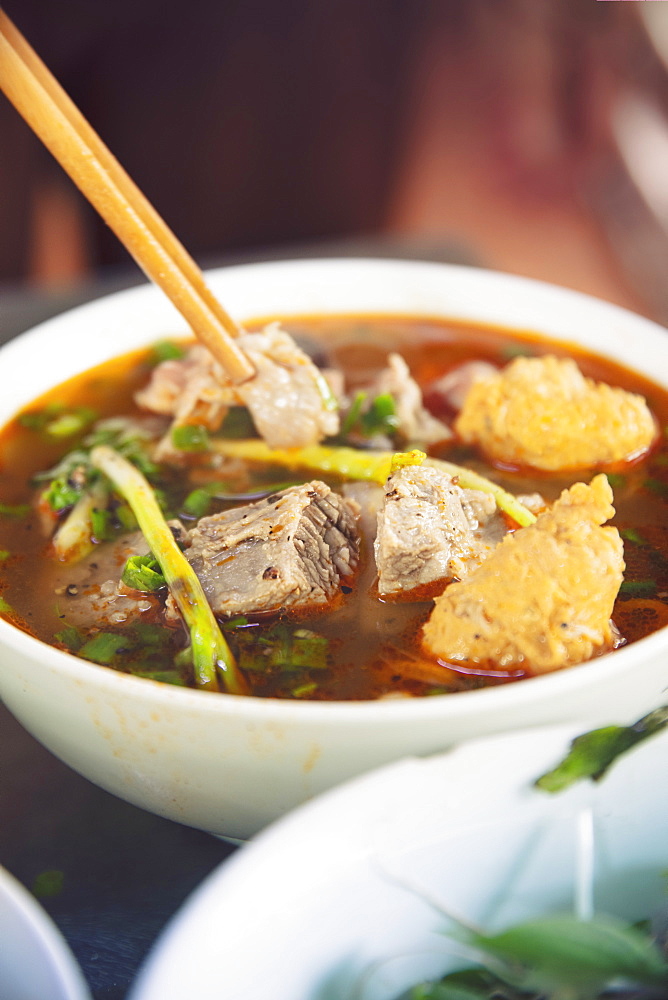 A steaming dish of Bun Bo Hue, the spicy local beef broth or hotpot, in a local restaurant, Hue, Vietnam, Indochina, Southeast Asia, Asia