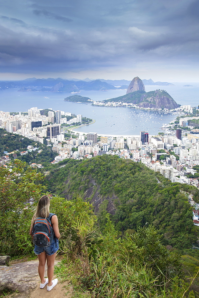 A female hiker looking out over the landscape of Rio to Sugar Loaf mountain from Tijuca National Park, Rio de Janeiro, Brazil, South America