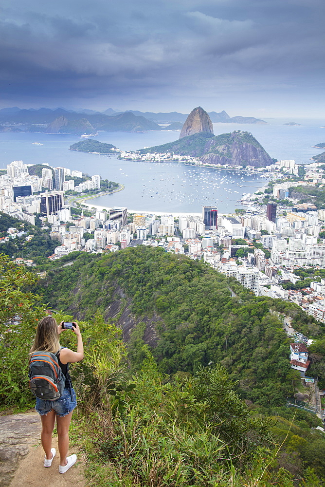 A female hiker looking out over the landscape of Rio to Sugar Loaf mountain from Tijuca National Park, Rio de Janeiro, Brazil, South America