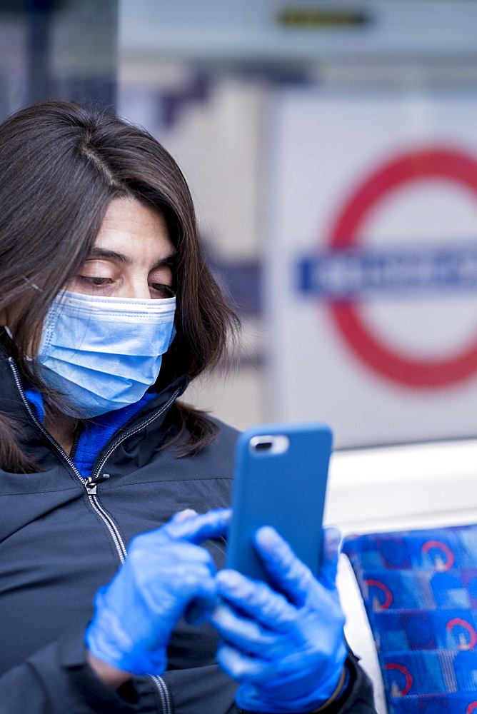 A woman wearing a protective hygiene (pollution) face mask on the London Underground subway system, London, England, United Kingdom, Europe