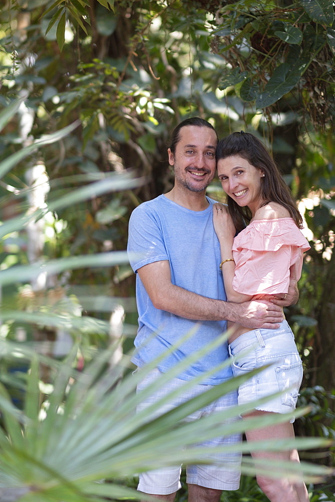 Tropical forest or hotel garden setting and middle-aged couple holding each other and happy together, Bahia, Brazil, South America