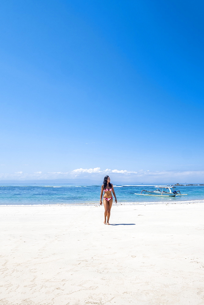 A beautiful Asian woman solo traveller in a bikini on a pristine tropical beach, Bali, Indonesia, Southeast Asia, Asia