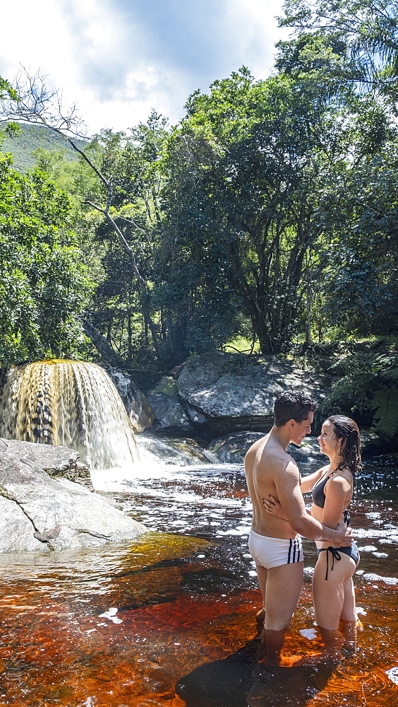 A young heterosexual Latin couple in love enjoying a swim in a mountain stream in pristine rainforest, Minas Gerais, Brazil, South America