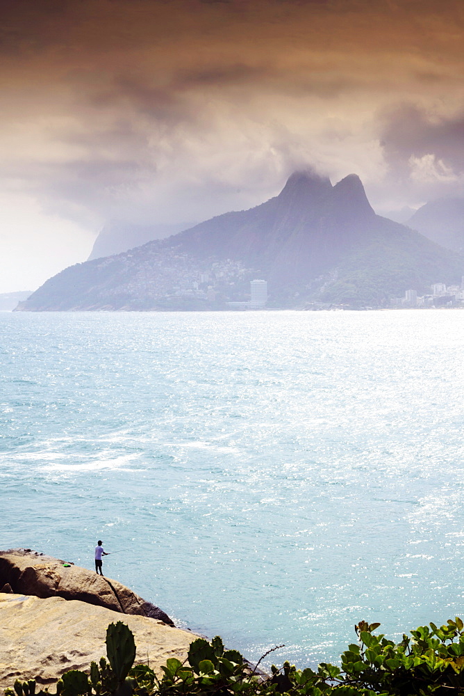 A fisherman on the Arpoador rocks next to Ipanema beach, Rio de Janeiro, Brazil, South America