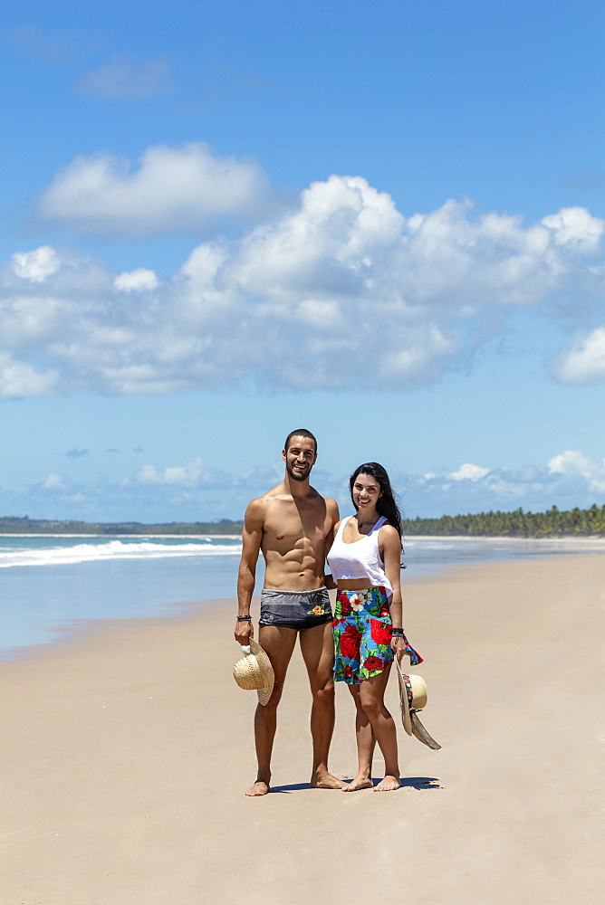 A good-looking Hispanic (Latin) couple on a deserted beach smiling to camera, Brazil, South America