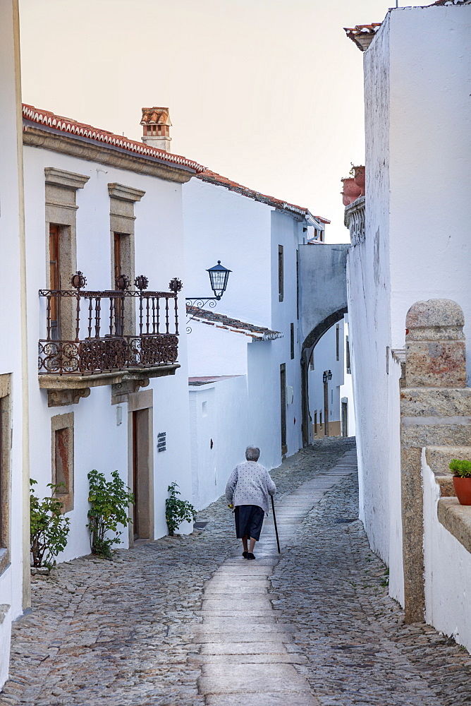 An old woman walking along an alley in the mountain village of Marvao in the Alentejo, Portugal, Europe