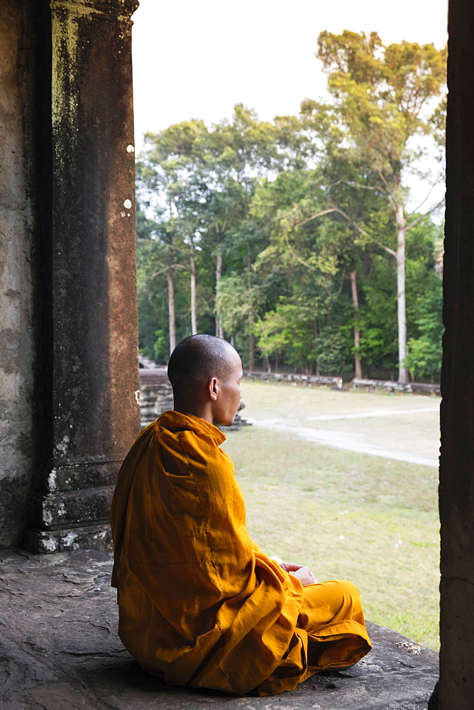 Buddhist monk sitting in a colonnaded corridor in a temple in Angkor Wat, UNESCO World Heritage Site, Siem Reap, Cambodia, Indochina, Southeast Asia, Asia