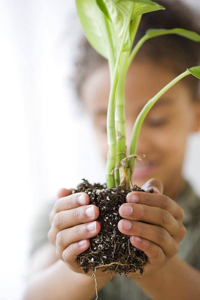 Mixed Race girl holding plant